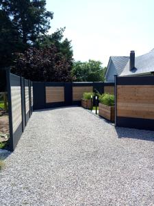 a driveway with a black fence and a wooden gate at La suite détendue in Saint-Blimont