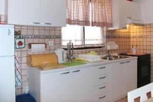 kuchnia z białymi szafkami i zlewem w obiekcie Family friendly apartments with a swimming pool Maslinica, Solta - 5180 w mieście Maslinica