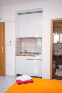 - une cuisine avec des placards blancs et un évier dans l'établissement Apartments by the sea Selce, Crikvenica - 5206, à Selce