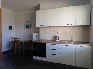 Apartments by the sea Cove Saplunara, Mljet - 4896 في Maranovići: مطبخ مع دواليب بيضاء ومغسلة