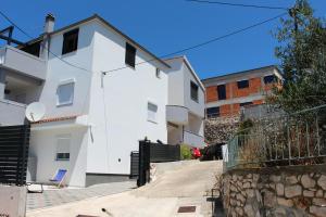 a white building with a fence next to it at Family friendly apartments with a swimming pool Tisno, Murter - 5073 in Tisno
