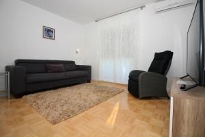 a living room with a couch and a chair at Family friendly apartments with a swimming pool Tisno, Murter - 5073 in Tisno