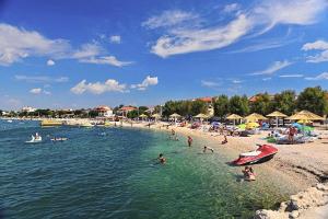 a beach with a bunch of people in the water at Apartments with parking space Vrsi - Mulo, Zadar - 5796 in Vrsi