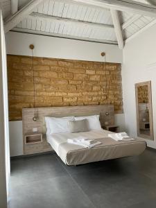 1 dormitorio con cama y pared de ladrillo en Oneira Rooms, en Agrigento