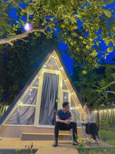 a man and a woman sitting in front of a tent at Tam Tinh Vien Homestay in Hue