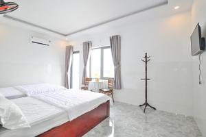 een witte slaapkamer met een bed en een televisie bij Ruby Hotel - Tân Uyên - Bình Dương in Hoi Nghia