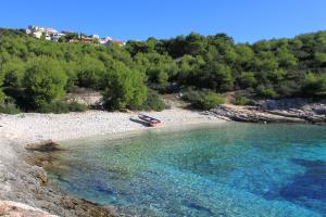 a boat in the water on a rocky beach at Apartments with a parking space Rukavac, Vis - 8836 in Vis
