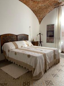 ein Schlafzimmer mit einem großen Bett mit Ziegelwand in der Unterkunft Dimora Ferraris in Càbras