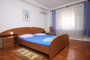 a bedroom with a bed with blue sheets and a window at Apartments by the sea Maslenica, Novigrad - 6568 in Jasenice