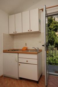 a kitchen with white cabinets and a sink at Apartments by the sea Podgora, Makarska - 6774 in Podgora
