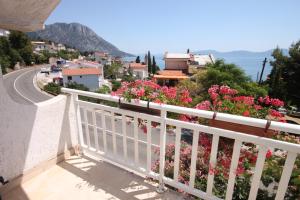 uma varanda com flores cor-de-rosa e uma estrada em Apartments by the sea Brist, Makarska - 6813 em Brist
