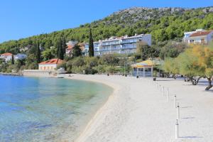 a beach with trees and buildings and the water at Apartments with a parking space Seget Vranjica, Trogir - 8507 in Seget Vranjica