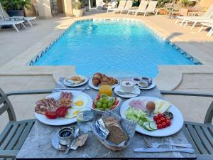 a table with breakfast food next to a swimming pool at IL-Gardjola Bed and Breakfast in Għarb