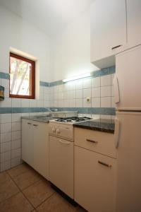 a white kitchen with a stove and a refrigerator at Apartments by the sea Zaostrog, Makarska - 6799 in Podaca