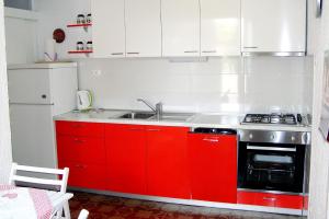 a kitchen with red cabinets and a sink at Apartments by the sea Mandre, Pag - 6515 in Kolan