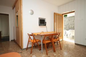 uma sala de jantar com uma mesa e cadeiras e uma televisão em Apartments by the sea Podgora, Makarska - 6664 em Podgora
