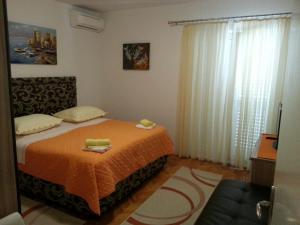 um quarto com uma cama com um cobertor laranja e uma janela em Apartments by the sea Podgora, Makarska - 6780 em Podgora