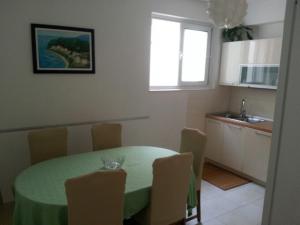 uma cozinha com uma mesa verde e cadeiras num quarto em Apartments by the sea Podgora, Makarska - 6780 em Podgora