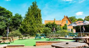 una zona de picnic con mesas de picnic y sombrilla en The George Hotel, Dereham en East Dereham