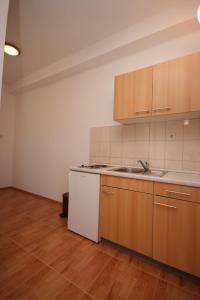 an empty kitchen with wooden cabinets and a sink at Apartments with a parking space Gradac, Makarska - 6724 in Gradac