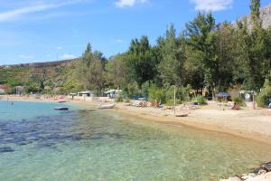 a beach with people sitting on the sand and water at Apartments by the sea Duce, Omis - 945 in Duće