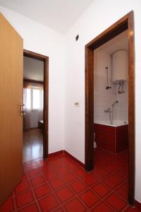 uma casa de banho com banheira e piso em azulejo vermelho em Apartments with a parking space Makarska - 6791 em Makarska