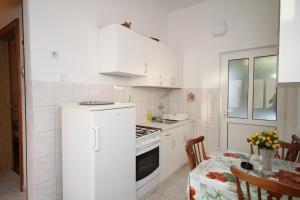 a kitchen with a white refrigerator and a table at Apartments with parking space Baska Voda, Makarska - 6854 in Baška Voda