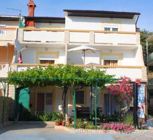 budynek z parasolem i kwiatami przed nim w obiekcie Apartments by the sea Pag - 6448 w mieście Pag