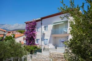 a white house with purple flowers on the side of it at Apartments by the sea Podgora, Makarska - 6671 in Podgora