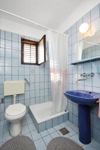 uma casa de banho em azulejos azuis com um WC e um lavatório em Apartments by the sea Pirovac, Sibenik - 6447 em Pirovac