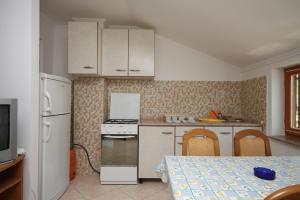 a kitchen with white appliances and a table and a table and chairs at Apartments by the sea Metajna, Pag - 6497 in Zubovići