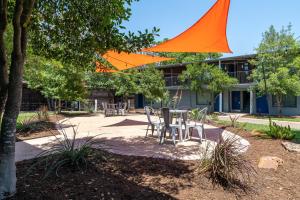 an orange umbrella over a table and chairs in front of a building at Abode Houston - Norfolk in Houston