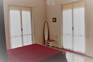 um quarto com 2 janelas grandes e uma cama vermelha em Appartamento Il Porticciolo em Marina dʼAndora