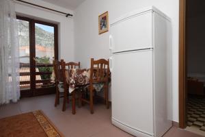 a kitchen with a white refrigerator and a table and chairs at Apartments and rooms by the sea Starigrad, Paklenica - 6591 in Starigrad