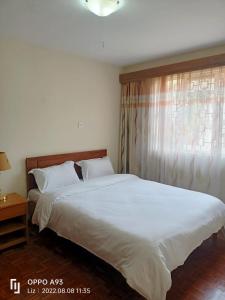 een slaapkamer met een groot wit bed en een raam bij China Garden in Nairobi