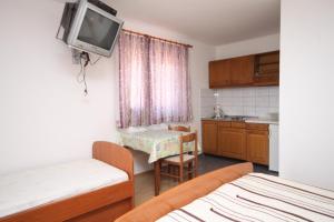 a room with two beds and a kitchen with a tv on the wall at Apartments with parking space Makarska - 6693 in Makarska