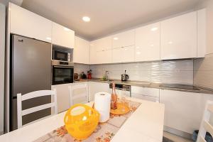 a kitchen with white cabinets and a yellow vase on a table at Apartments with a parking space Tucepi, Makarska - 6695 in Tučepi