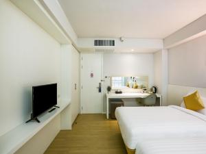 a bedroom with two beds and a desk and a television at Kitzio House Hotel Huai Kwang in Ban Na Song