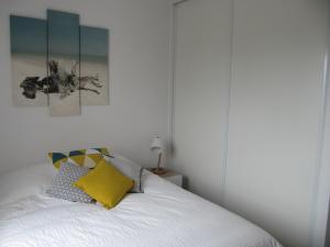 - une chambre avec un lit blanc et un oreiller jaune dans l'établissement BIDART CENTRE et PLAGE A PIED, à Bidart