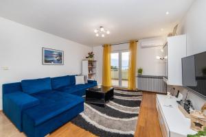 a living room with a blue couch and a tv at Apartments by the sea Podaca, Makarska - 6735 in Podaca