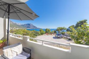 a balcony with an umbrella and a car in a parking lot at Apartments by the sea Podaca, Makarska - 6735 in Podaca