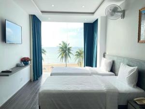 two beds in a bedroom with a view of the beach at Y Linh Hotel in Quy Nhon