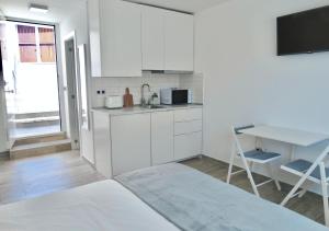 cocina con armarios blancos, mesa y escritorio en Apartamento único en El Sauzal - inolvidable!!!, en Sauzal