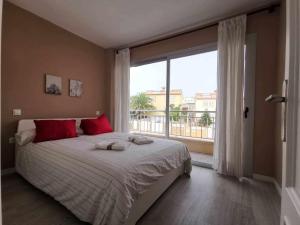um quarto com uma cama com almofadas vermelhas e uma grande janela em Apartamento en la Playa em Melenara