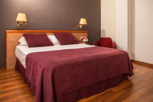 a bedroom with a large bed and a red chair at RVHotels Spa Vila de Caldes - Adults only in Caldes de Montbui