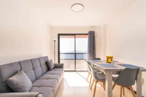 sala de estar con sofá y mesa con sillas en Apartamento con preciosas vistas al mar, en Melenara