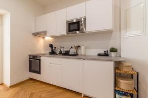 cocina con armarios blancos y microondas en Vienna City Apartment, en Viena
