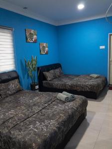 1 dormitorio con 2 camas y pared azul en RD Legend Hotel, en Port Dickson