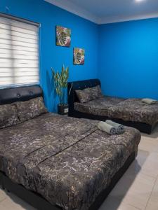 1 dormitorio con 2 camas y pared azul en RD Legend Hotel, en Port Dickson