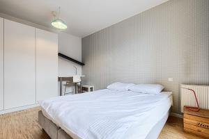 a bedroom with a large bed with white sheets at Loft Green by LookAp in Łódź